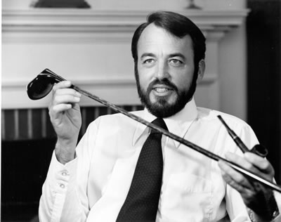 A man holding two pairs of sunglasses and one pair of glasses.