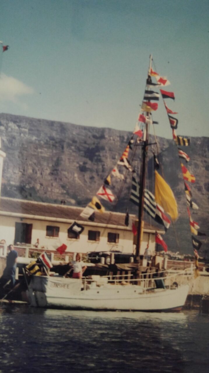 Boat with many flags, mountain backdrop.