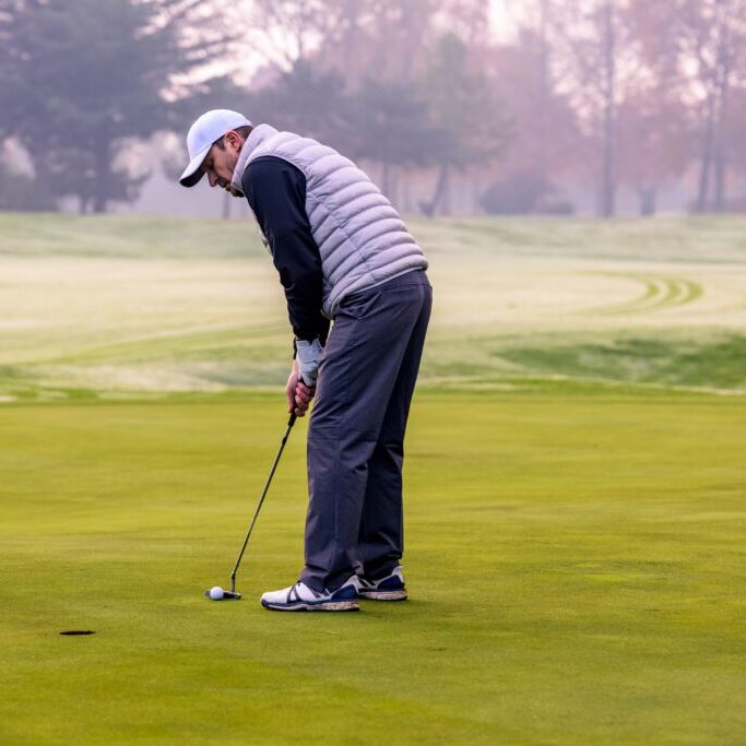 Close-up of a golf player who with a putt over the ball on the green